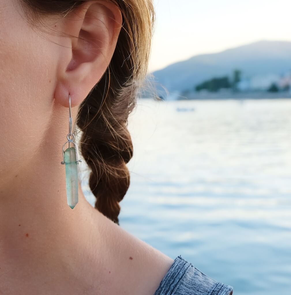 Aqua blue crystal earrings against the soft afternoon light.
